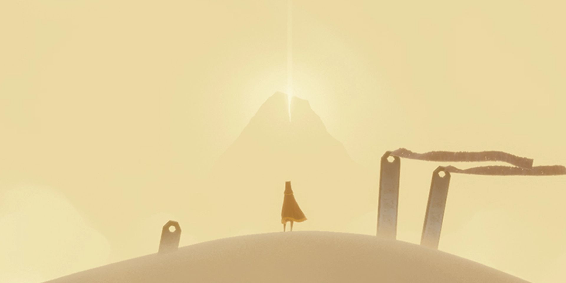The player character stands on a sand dune and looks at a glowing mountain in Journey.