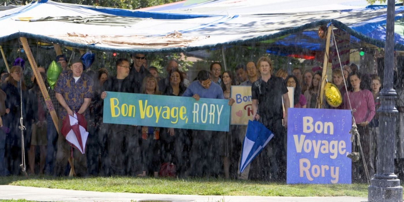 The residents of Stars Hollow holding up signs at Rory's graduation party on Gilmore Girls
