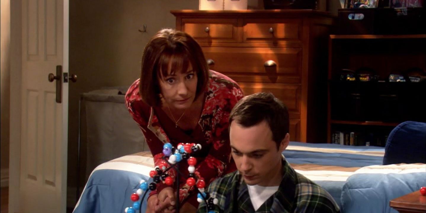 The Big Bang Theory - Mary leans down to talk to Sheldon, who sits on the floor in his bathrobe