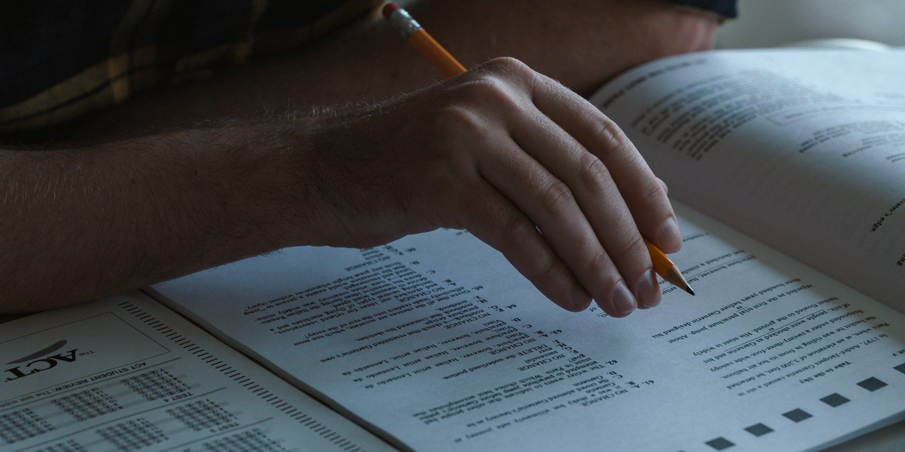Picture of an adult hand taking a test in Operation Varsity Blues The College Admissions Scandal