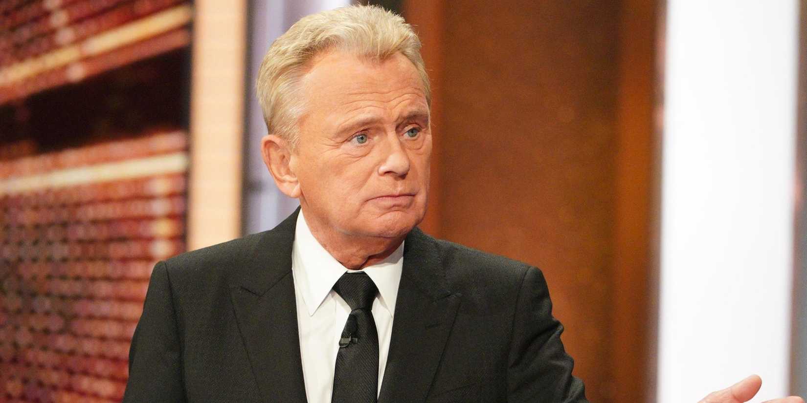 Pat Sajak raising his hand up on Wheel Of Fortune