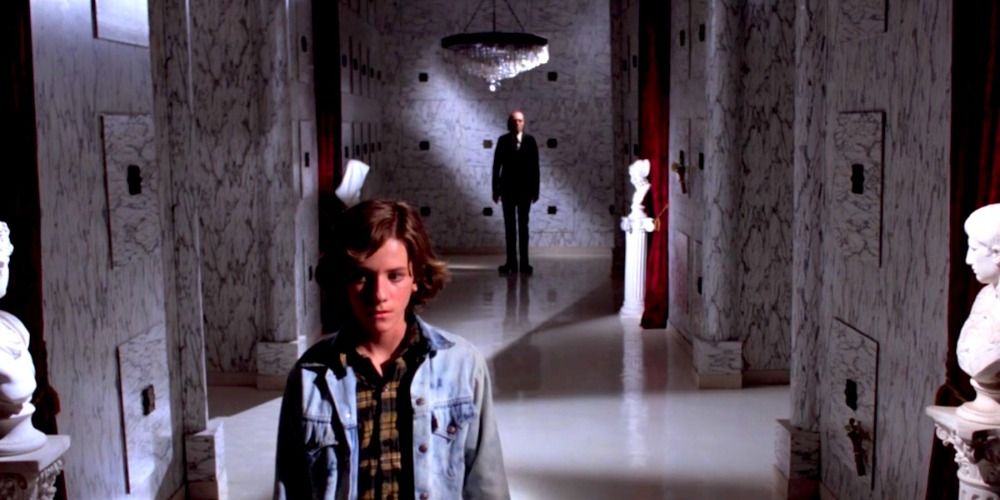Mike walking down the hall as a man in a black suit looks at him from behind in Phantasm