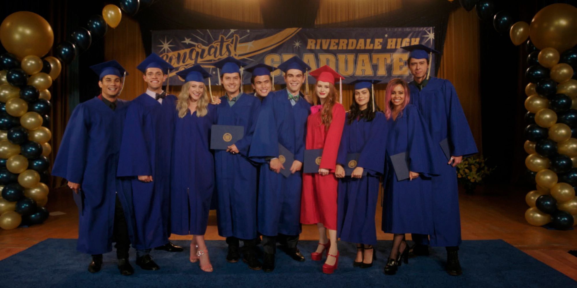 The Riverdale teens in their graduation gowns, standing in a row