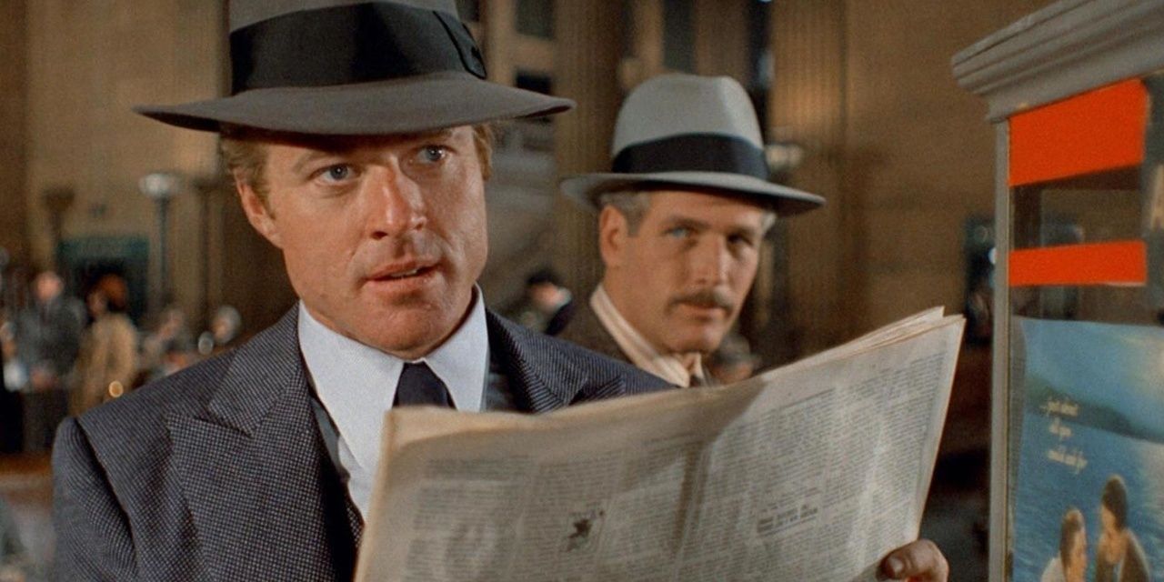 Robert Redford holding a paper as Paul Newman looks at him in The Sting