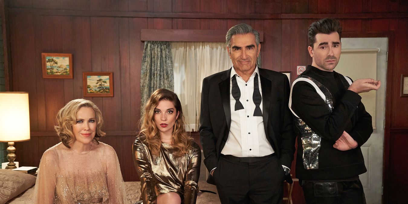 A promo picture for Schitt's Creek with the Rose family sitting in the motel