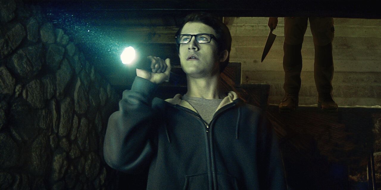 Dylan Minnette's character holding a flashlight in The Open House not realizing someone's behind him