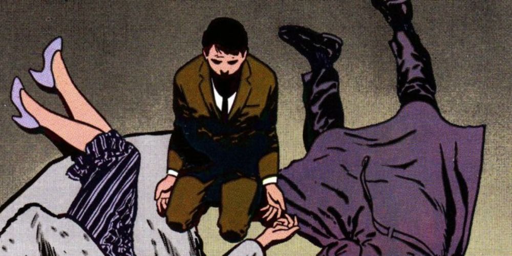 Bruce Wayne laying on the ground near the corpses of his parents