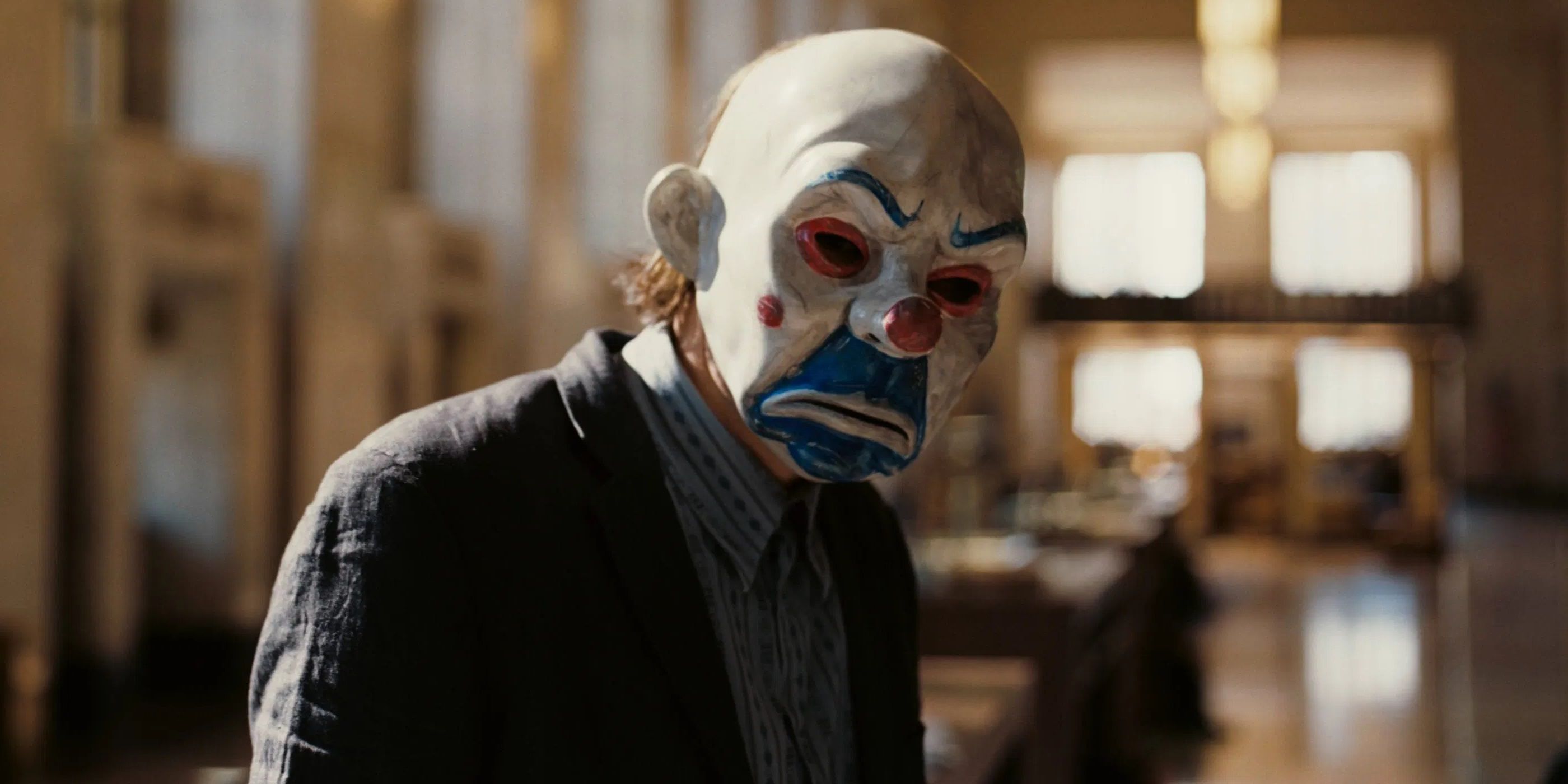 The Joker wearing a clown mask in the opening bank robbery scene of The Dark Knight