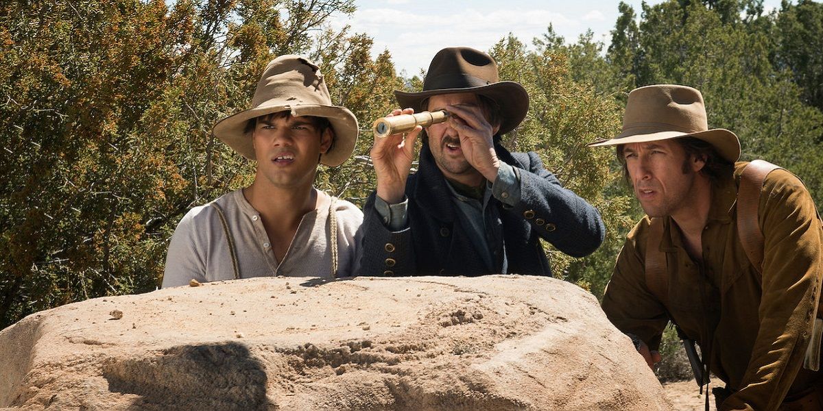 Adam Sandler and co behind a rock hiding and looking at something with a telescope in The Ridiculous 6 