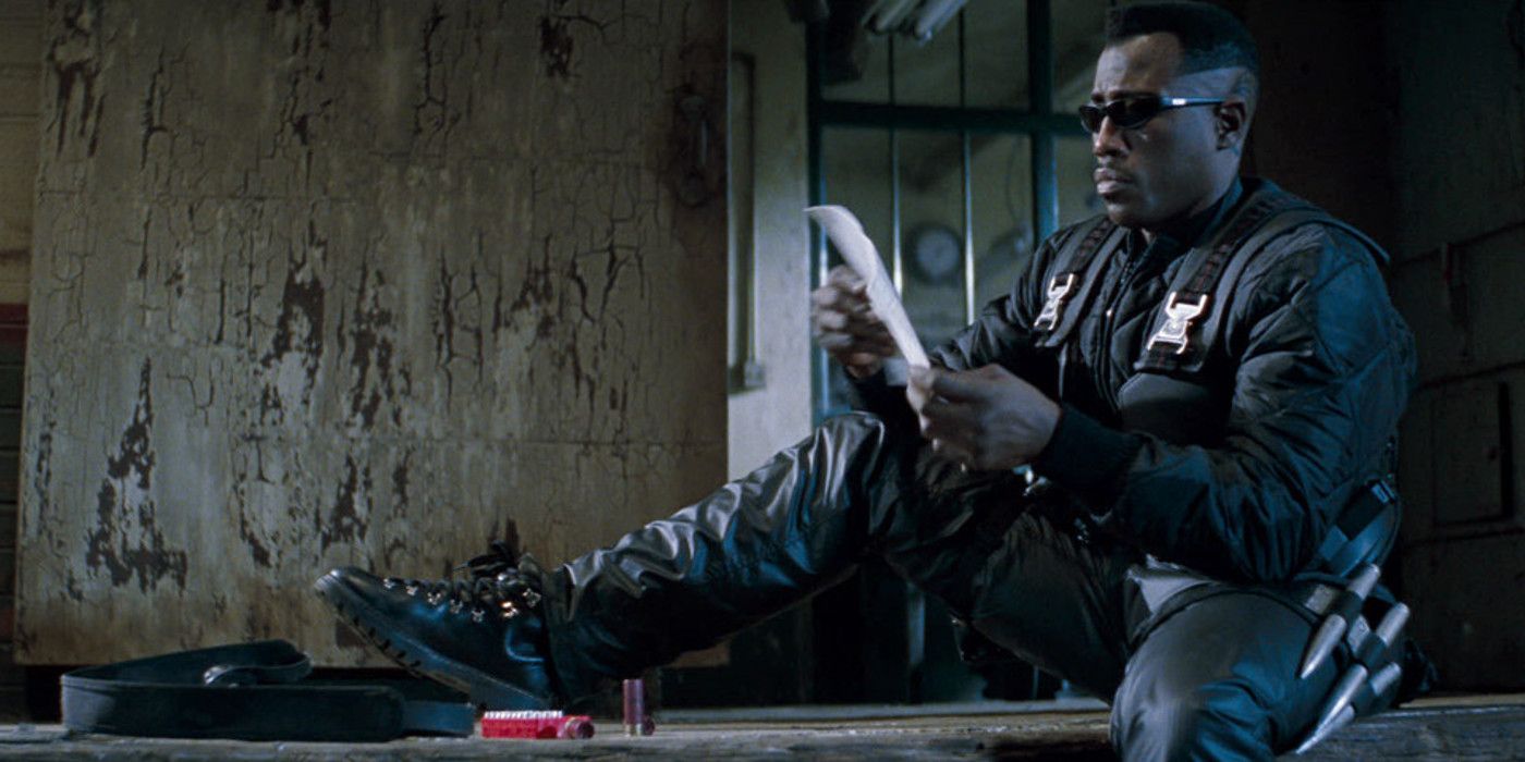 Blade sits and sharpens a weapon in Blade (1998).