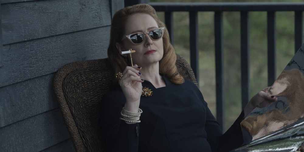 Zelda sitting on her porch with sunglasses on and smoking a cigarette