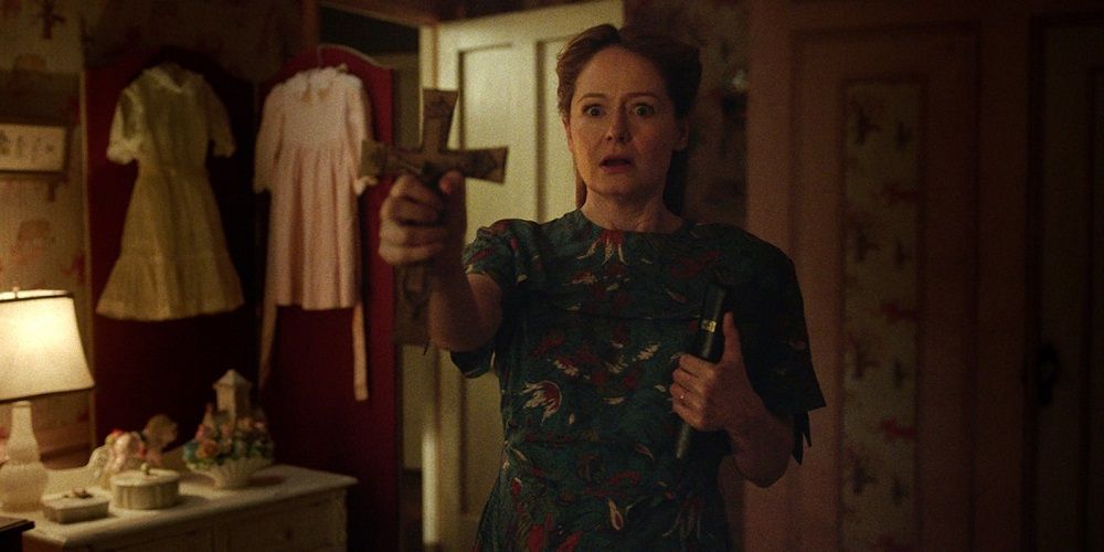 Esther holds out crucifix in Annabelle Creation