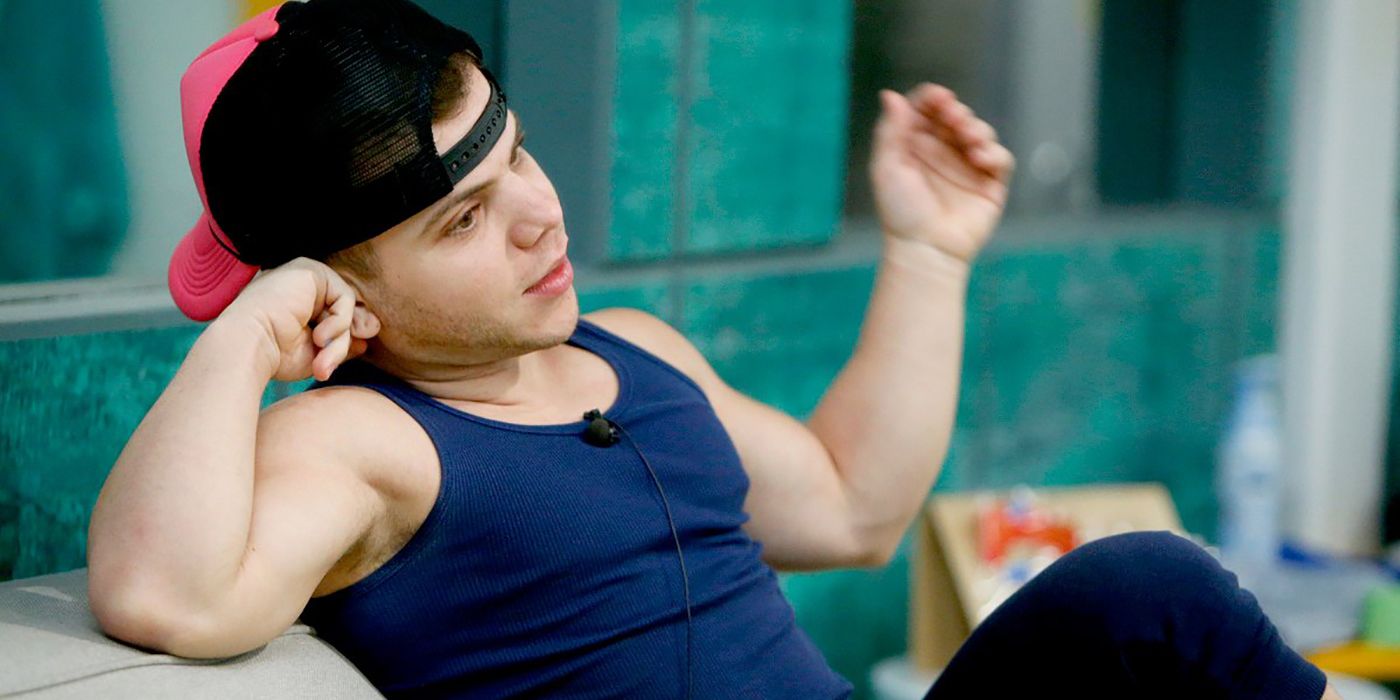 JC Mounduix from Big Brother sitting on a chair with a backwards hat and tank top