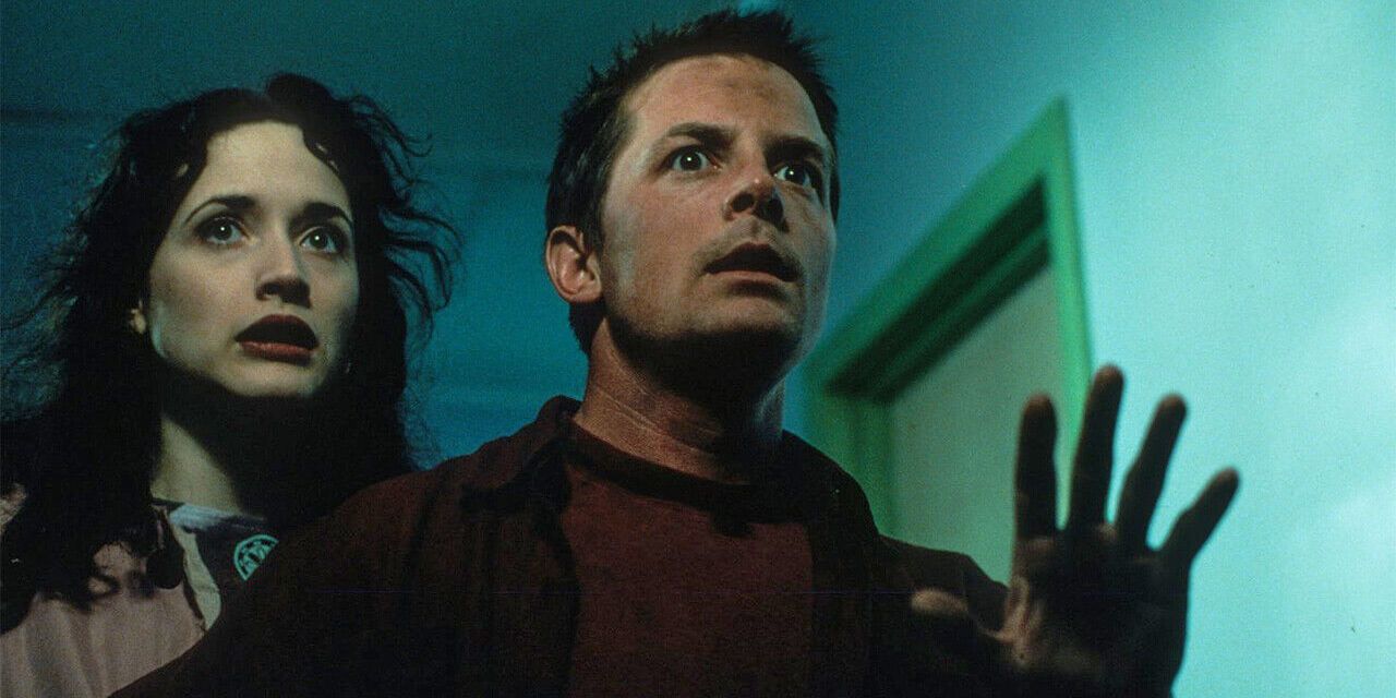 Frank with his hand up looking scared with Lucy standing behind him in The Frighteners