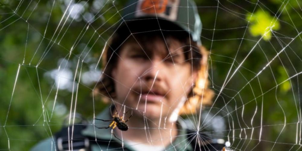 Josh McDermitt stands behind spiderweb with spider in it Creepshow