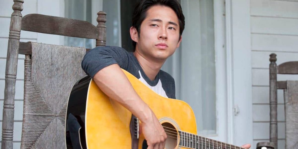 Glenn sitting on a chair holding a guitar in The Walking Dead