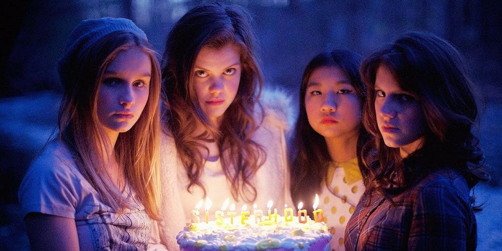 Four witches hold birthday cake in Sisterhood of the Night