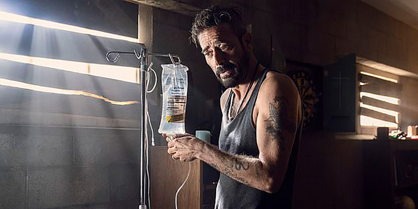 Negan in a tank top holding Lucille's bag of treatment