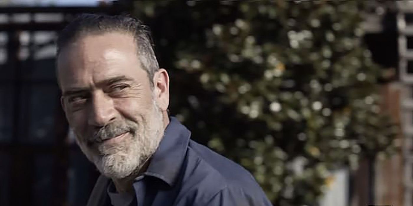 Negan looking at someone off to the side, a smug look on his face and closed mouth smile