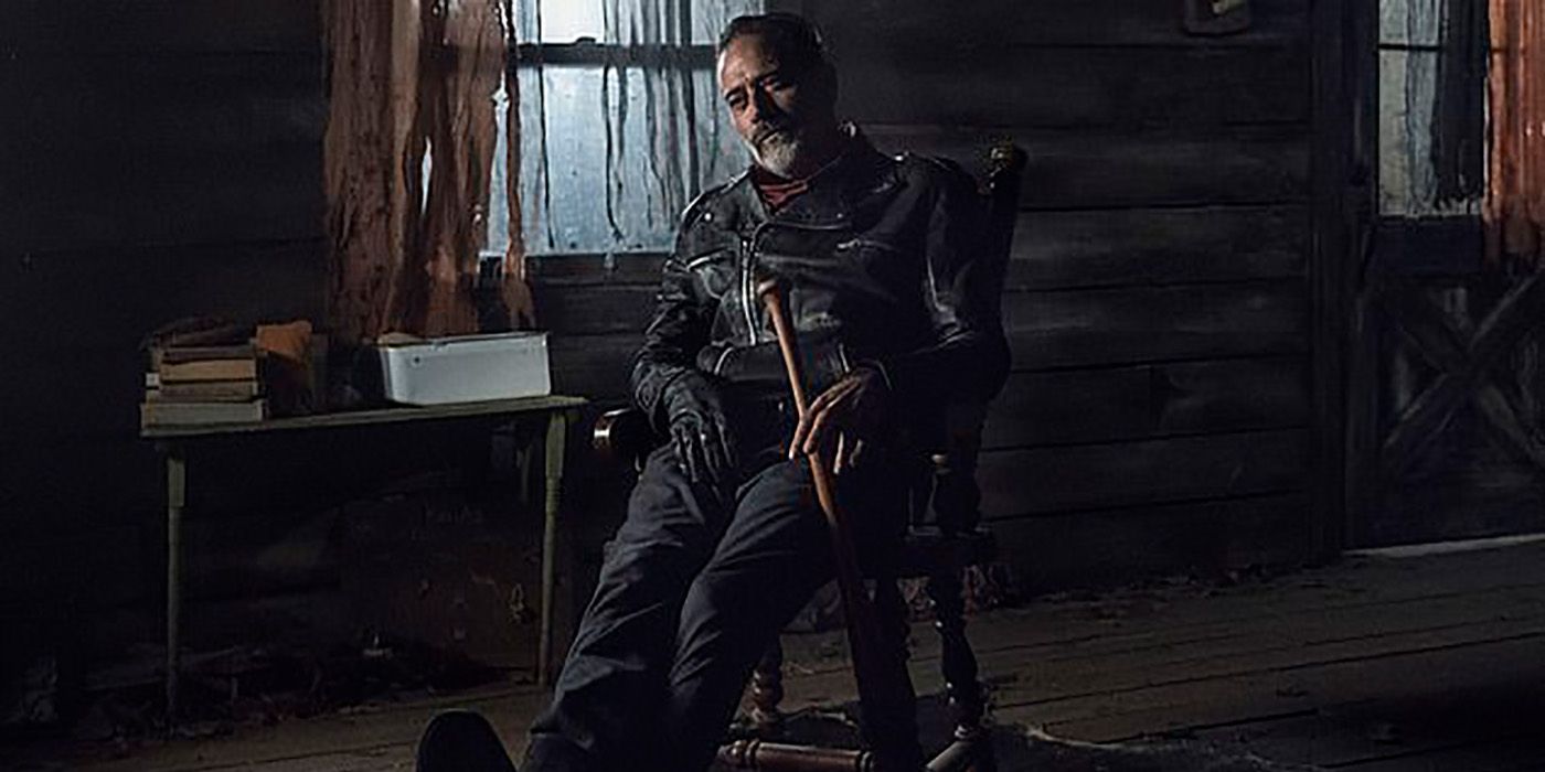 The Old Negan with the black leather jacket and Lucille the bat slumped down in a chair, a smug look on his face