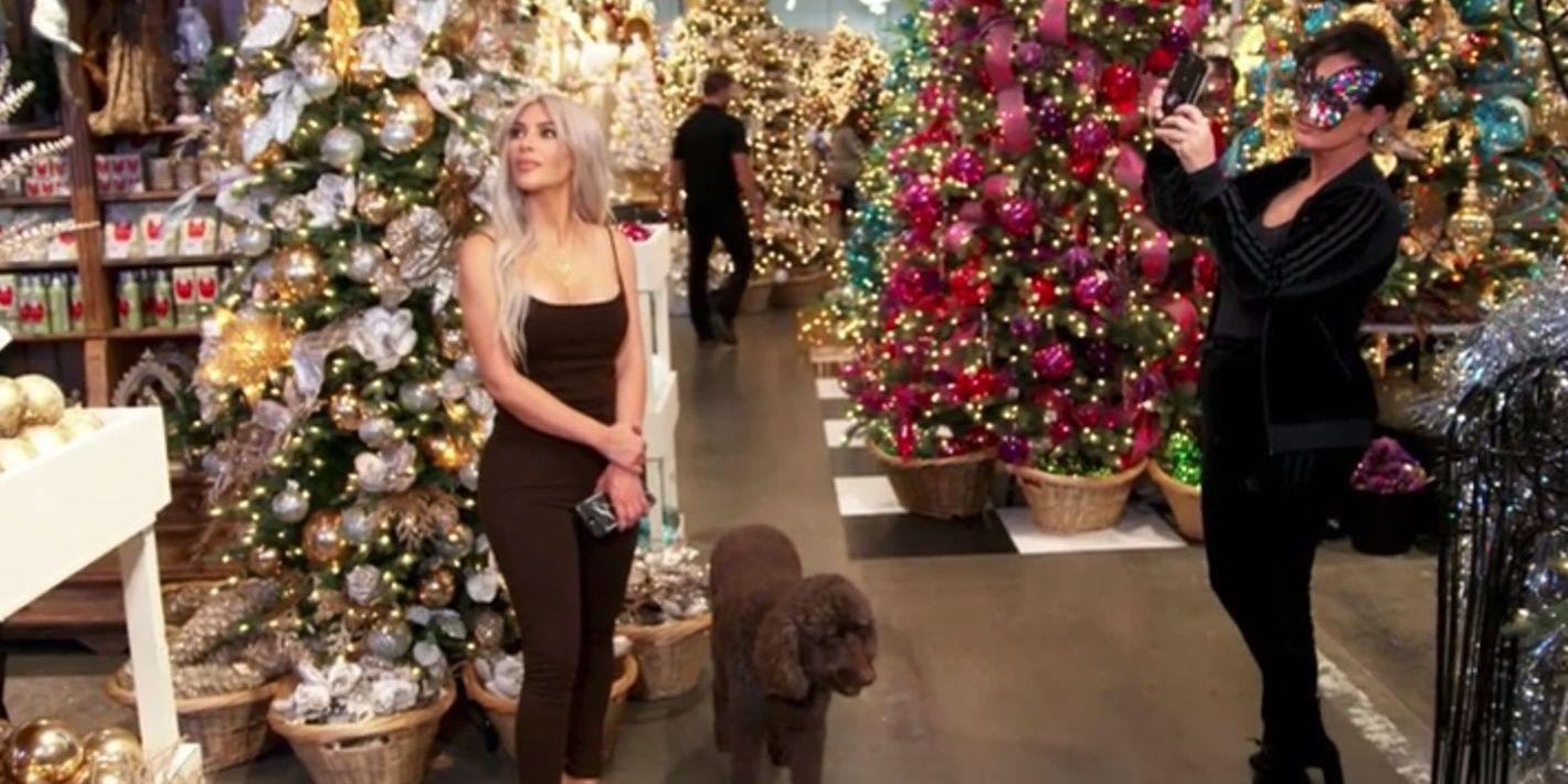 Kim in a black jumpsuit and Kris in a festive mask surrounded by festive decorations