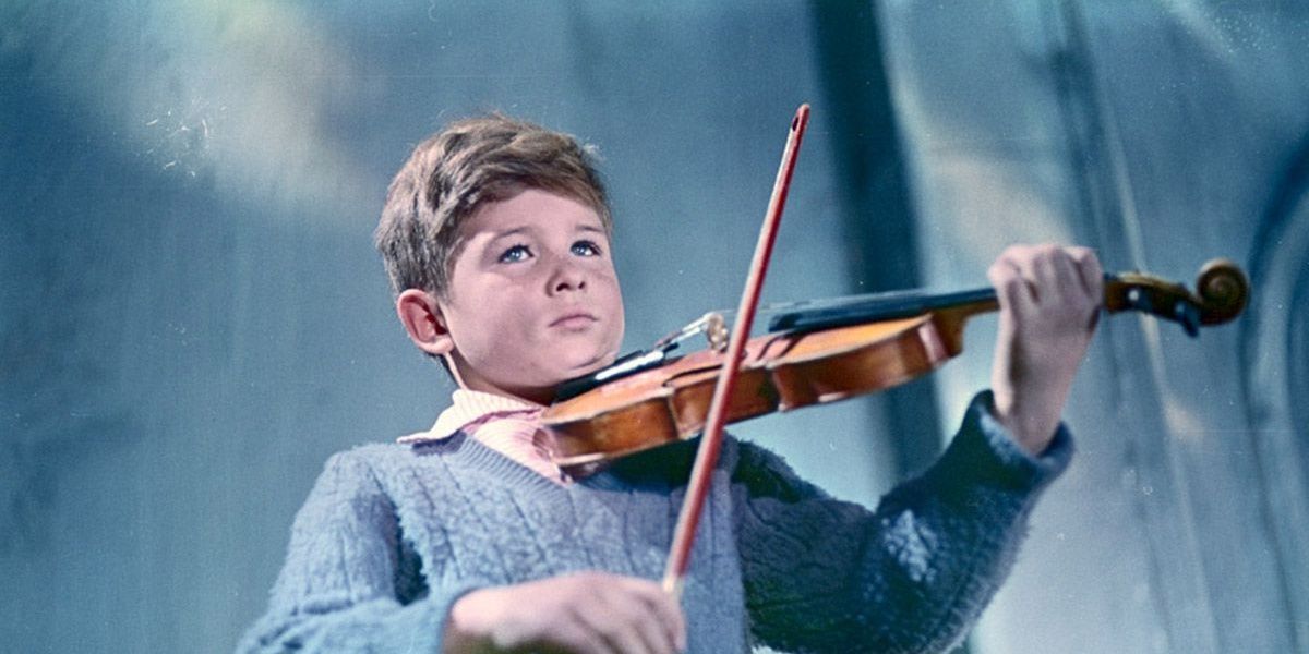 A boy playing a violin in a still from The Steamroller and the Violin