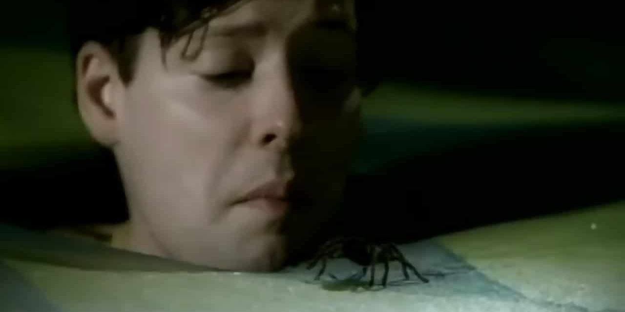 A still from Sex and Candy featuring a man staring at a spider.