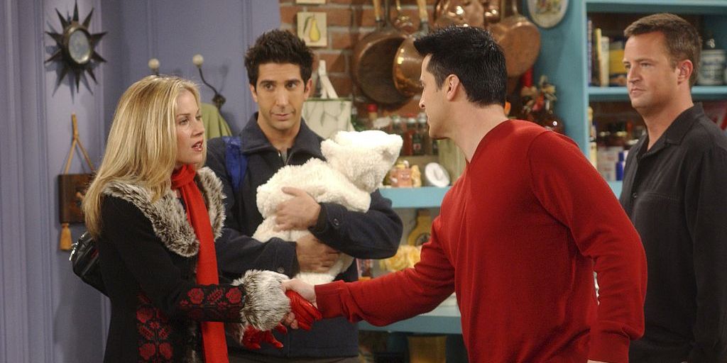 Amy Green aperta as mãos de Joey em Friends enquanto Ross e Chandler assistem em Friends.
