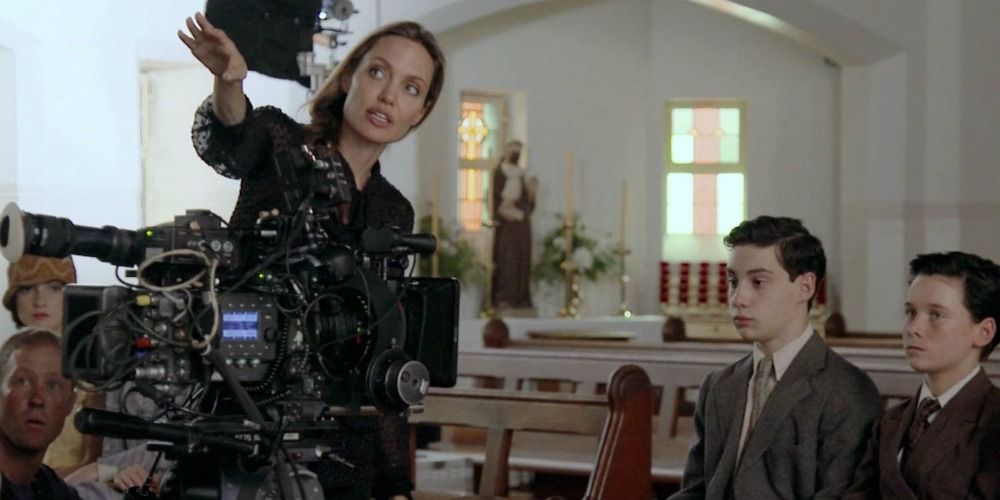 Angelina Jolie directing two young actors as she motions to something off-camera