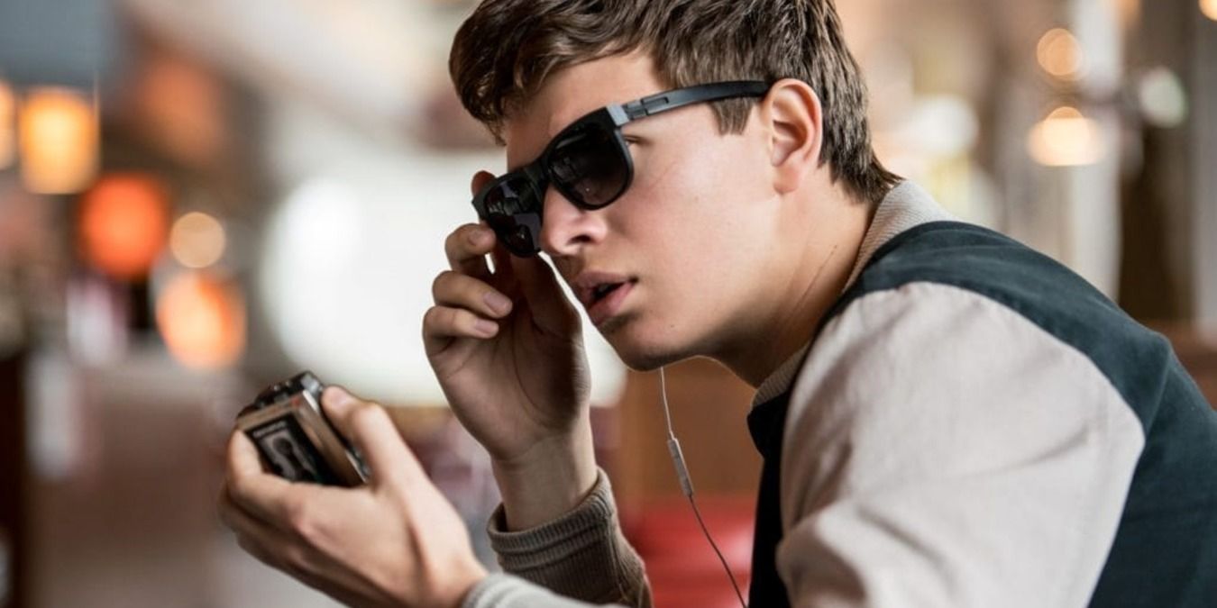 Ansel Elgort as Baby, holding his music player with sunglasses on