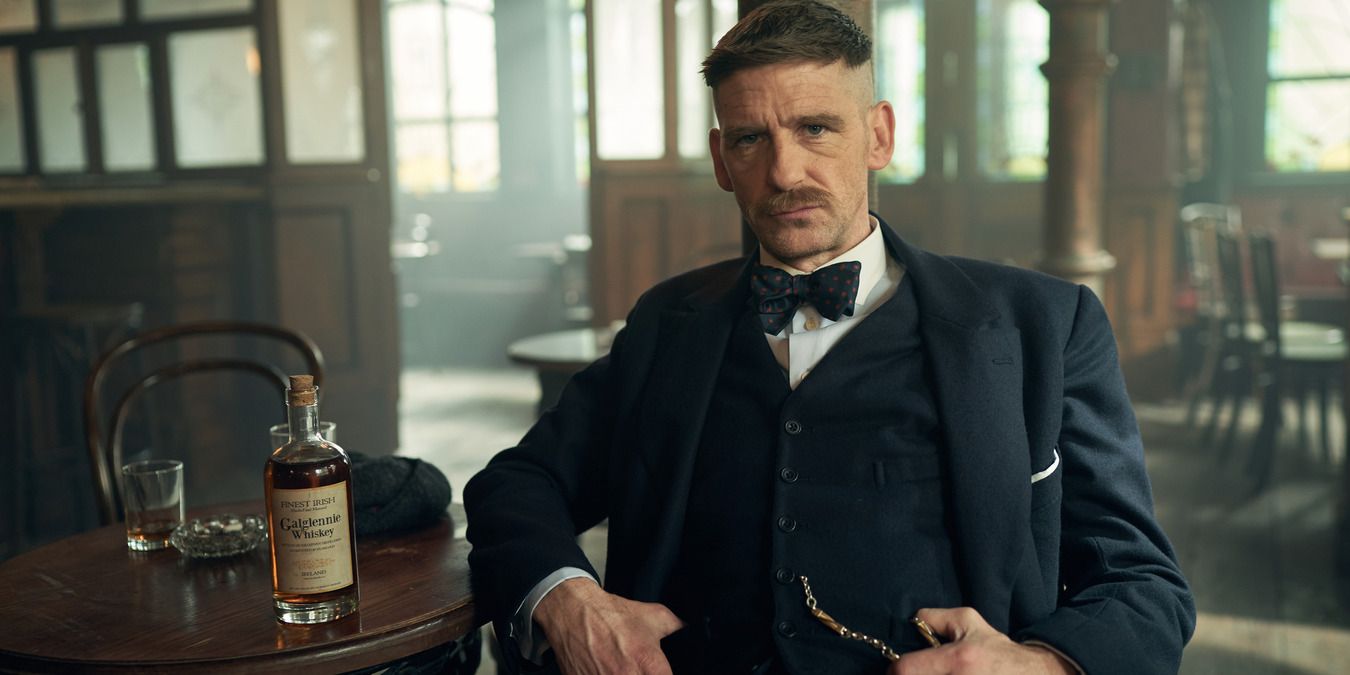 Arthur Shelby sitting with a bottle of whiskey at the Garrison pub