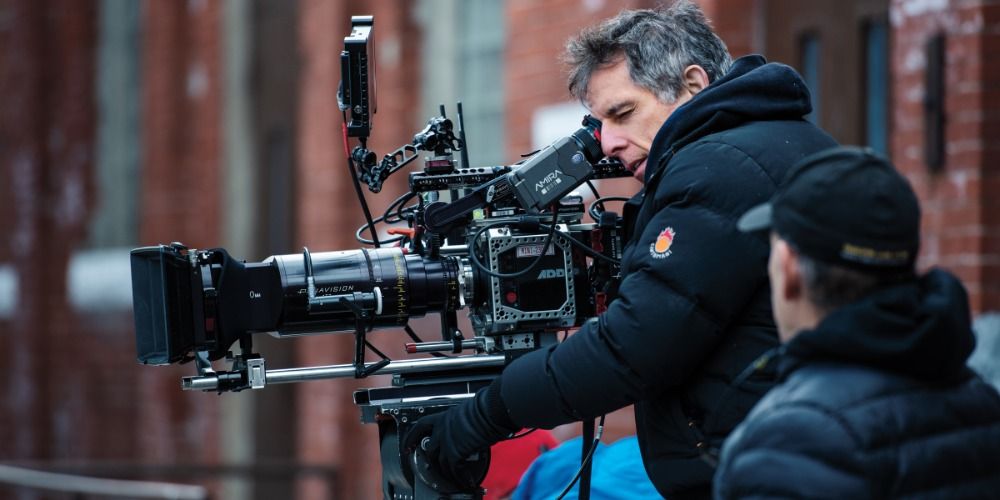 Ben Stiller bundled up and looking through a director's camera