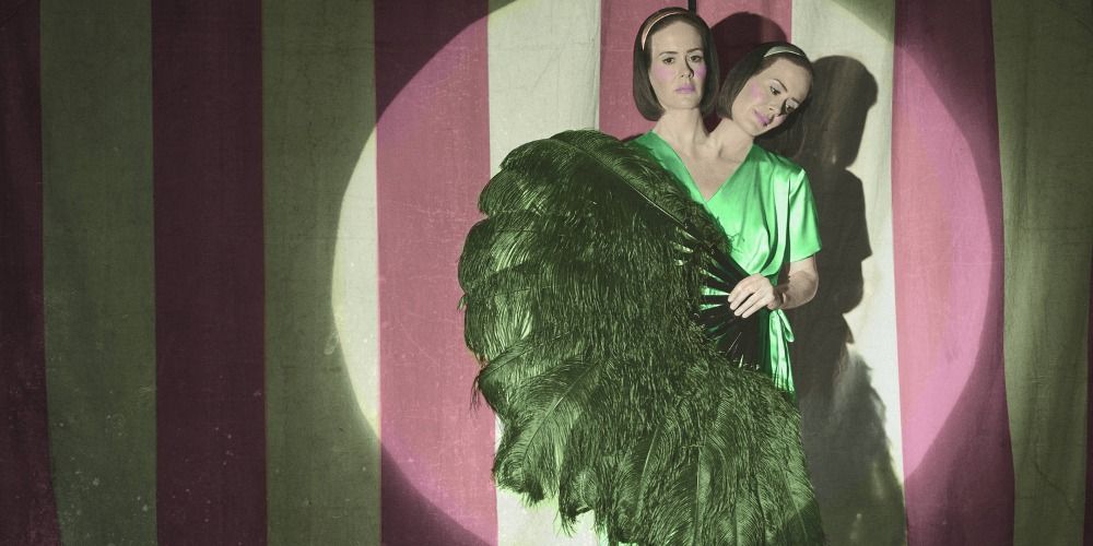 Bette &amp; Dot posing on stage with a large feather in AHS.