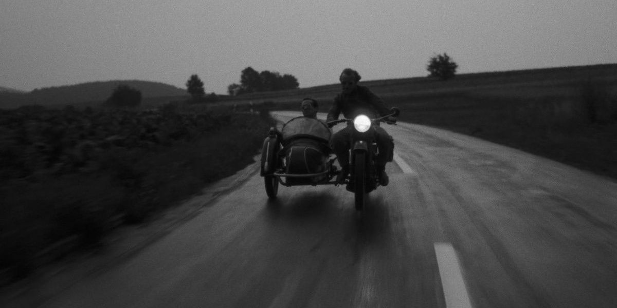 Bruno and Robert traveling in a motorcycle and a sidecar on an empty road, a still from Kings of the Road