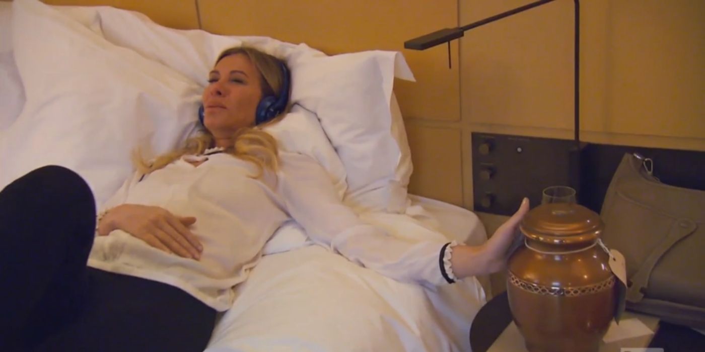 Carole laying down touching her husband's urn on a sad episode of RHONY