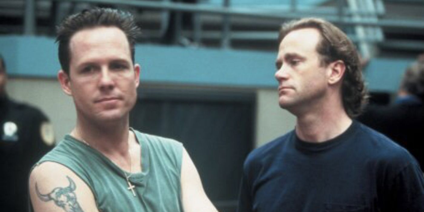 Dean Winters in prison in Oz, standing with his arms crossed.