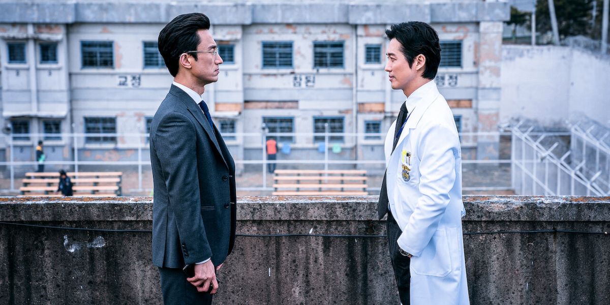 Yi-Je com casaco de médico de frente para Min-Sik no telhado em Doctor Prisoner 