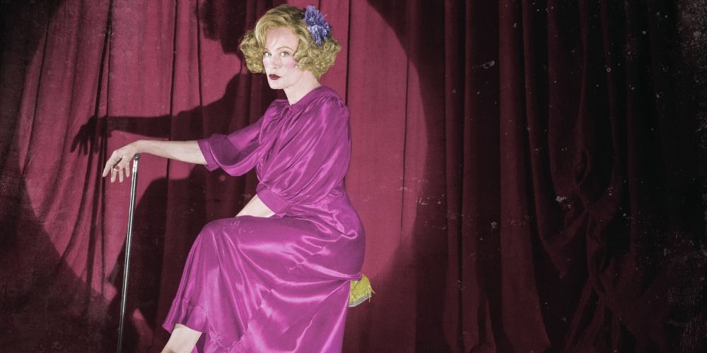 Elsa Mars holding onto a cane and posing for the camera on stage in Freak Show