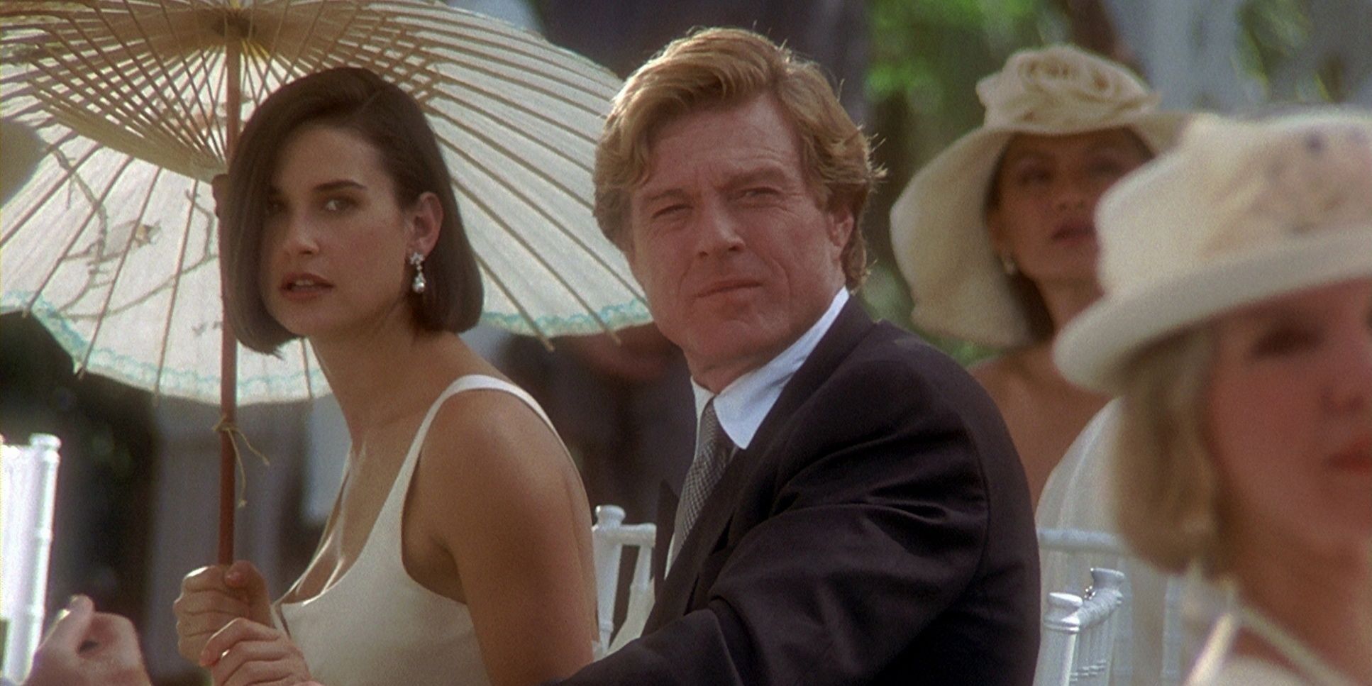 John (Robert Redford) and Diana (Demi Moore) holding an unbrella at a dinner table in Indecent Proposal