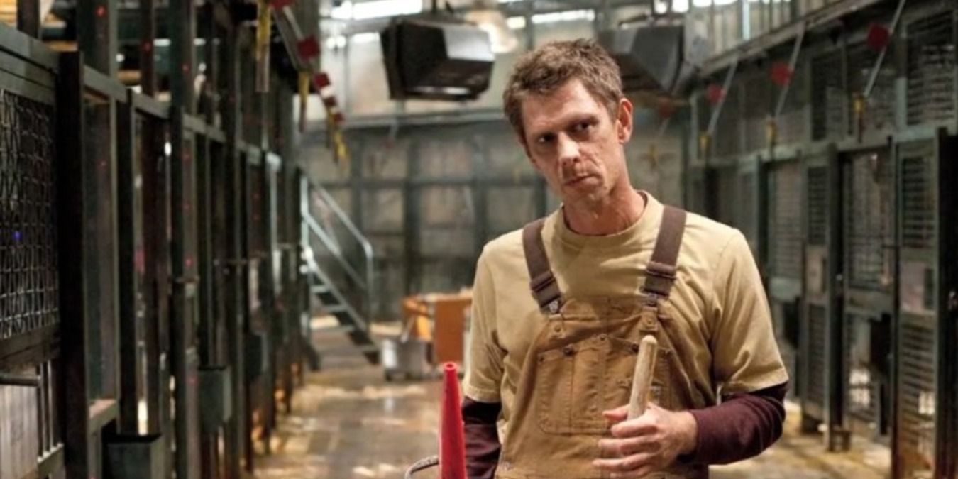 Jamie Harris as Rodney, holding a broom in the hall of cages