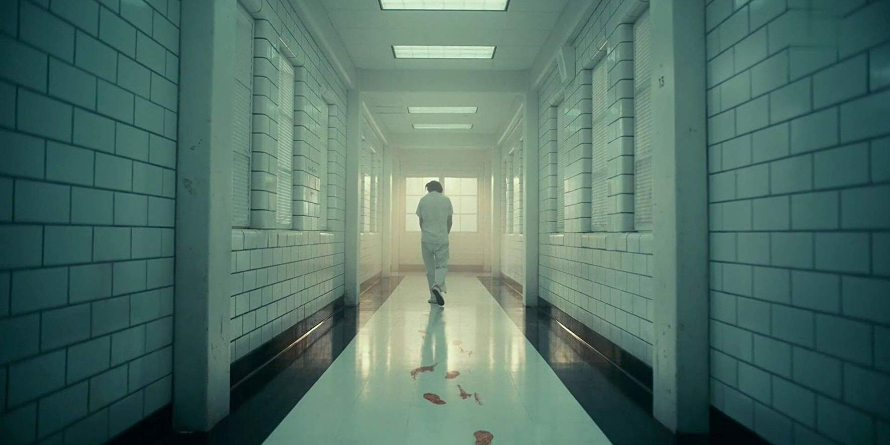Arthur walks through a white hall in Arkham Asylum in Joker