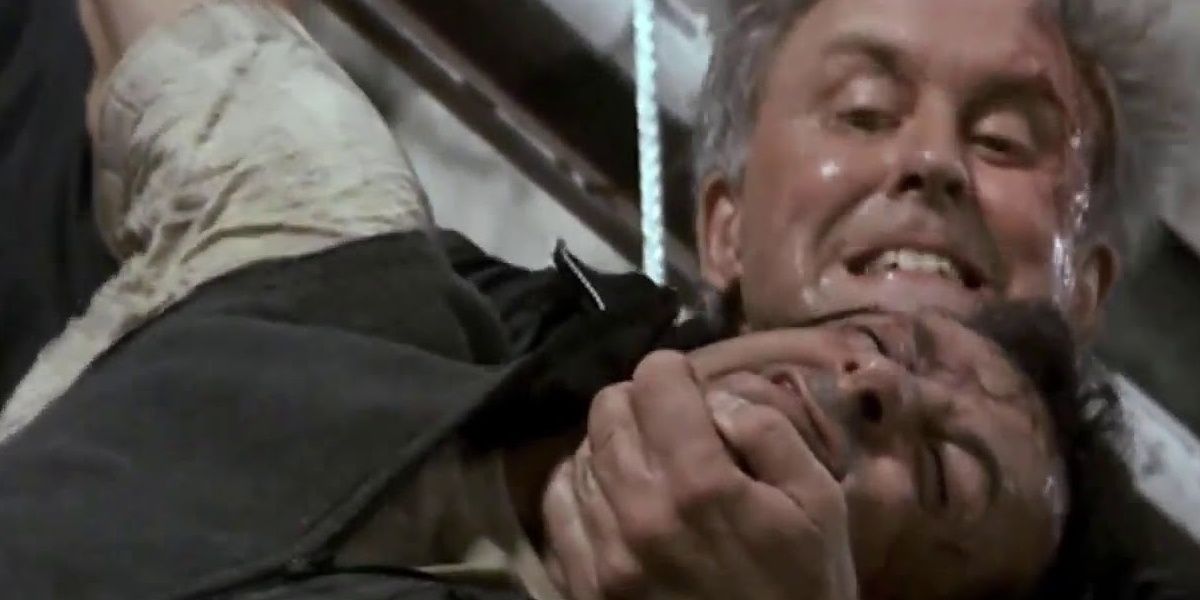 John Lithgow pressing his hand against Sylvester Stallone's chin in a still from Cliffhanger