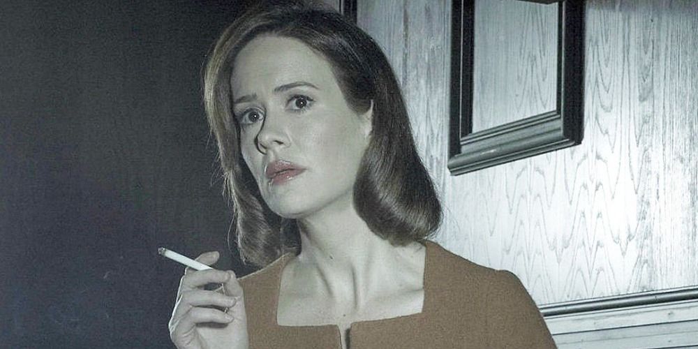 Lana Winters smoking a cigarette and looking at something off-cameras in AHS