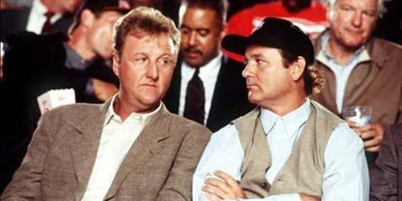 Larry Bird and Bill Murray sitting in the crowd at a basketball game in Space Jam