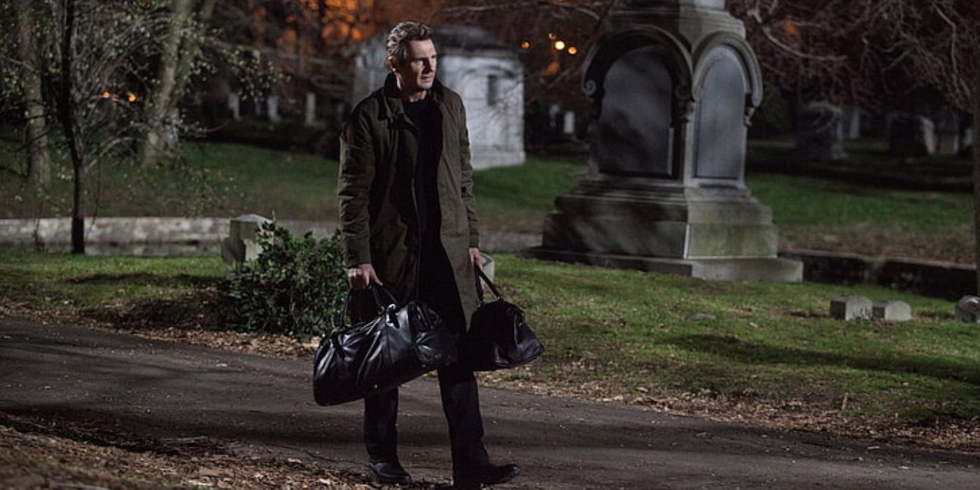 Liam Neeson walking with two duffel bags in his hand, in a still from A Walk Among The Tombstones