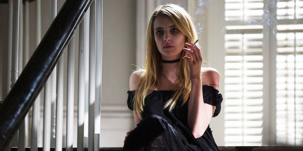 Madison sitting on a staircase while holding a cigarette in Coven