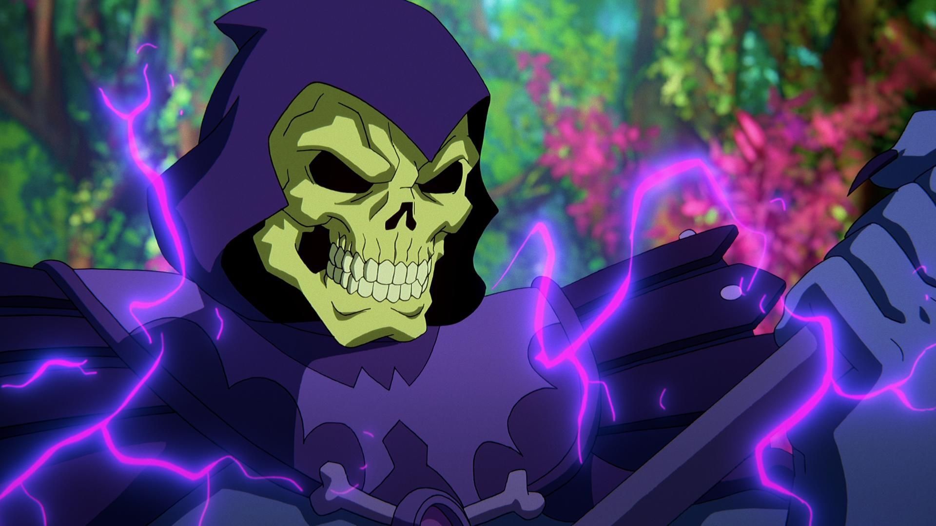 In a CG animated still from Masters of the Universe: Revelation, Skeletor, who wears a purple cloak and hood over his skull, stands in a forest with bright foliage as he grips his spear as purple electricity sparks around him.