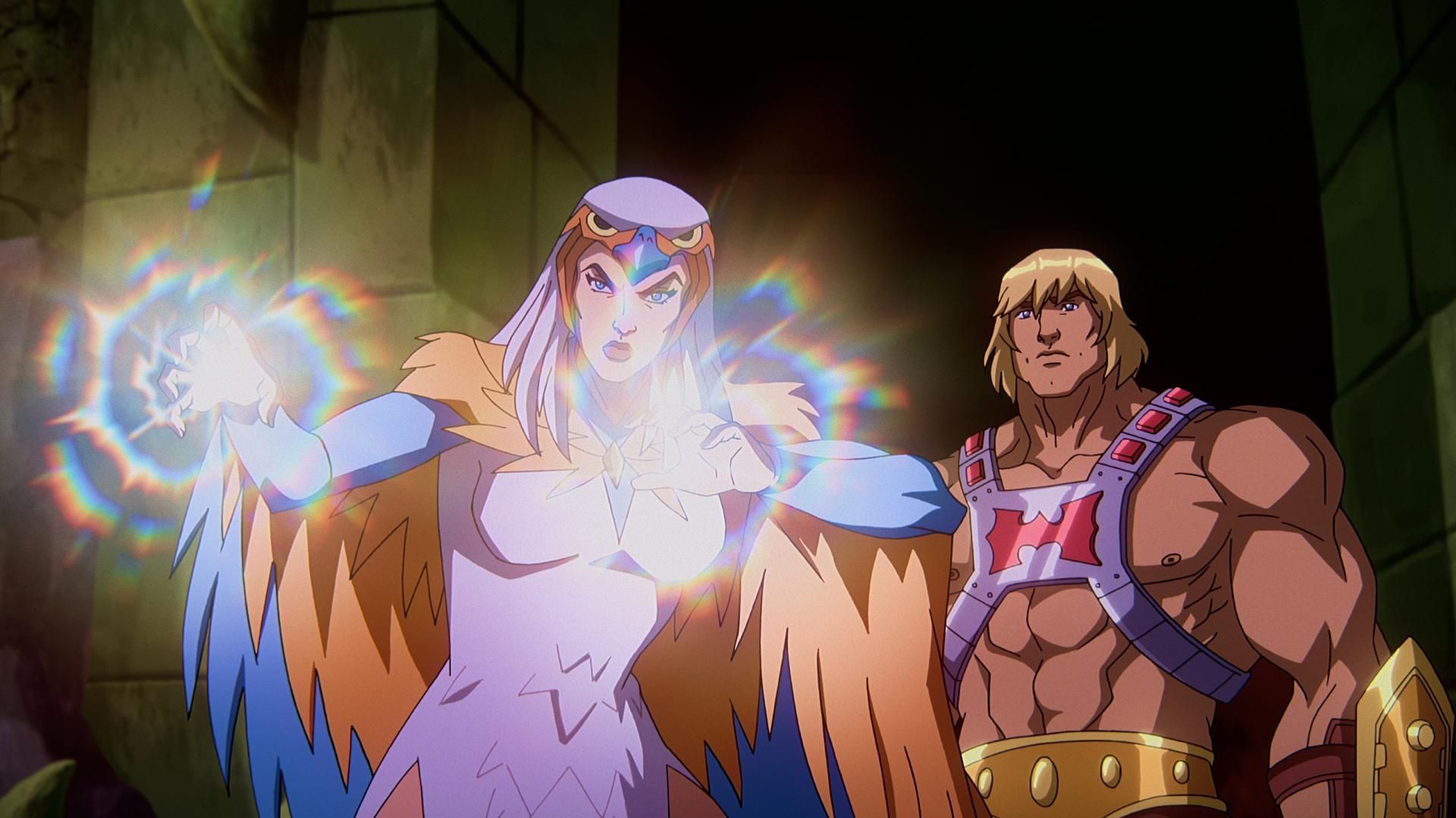 In a CG animated still from Masters of the Universe: Revelation, He-Man (right) stands behind Sorceress (left) in a stone room lit only by the light coming from SorceressesÕ hands. Sorceress has her palms outstretched in front of her and wears a white dress, a falcon-like hood over head and orange and blue wings. He-Man wears a silver chest plate with a red &quot;H&quot; in the center, a golden armored belt and wrist plates.