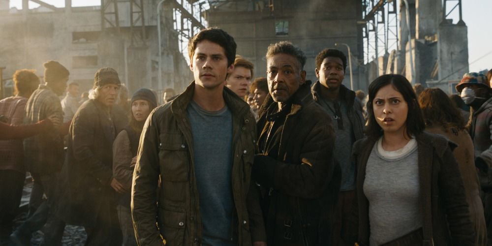 Thomas, Jorge and Teresa standing in front of a crowd and looking at something off-camera in Maze Runner: Death Cure
