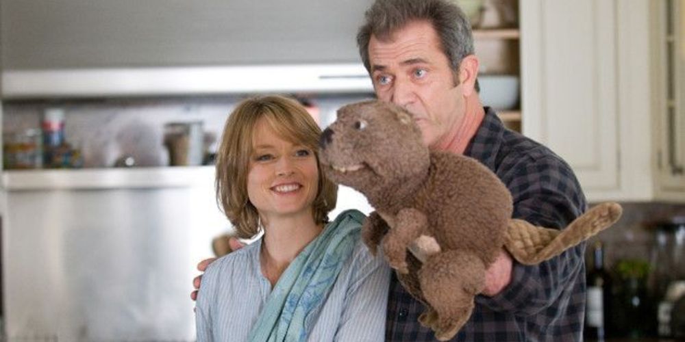 Mel Gibson with a beaver hand puppet as Jodie Foster smiles at him in a still from The Beaver.